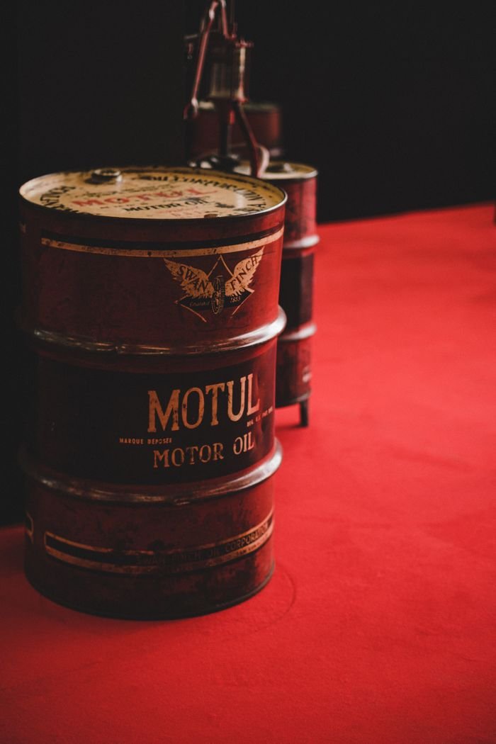 About A close-up of a rusty oil barrel in an industrial setting with a red backdrop.